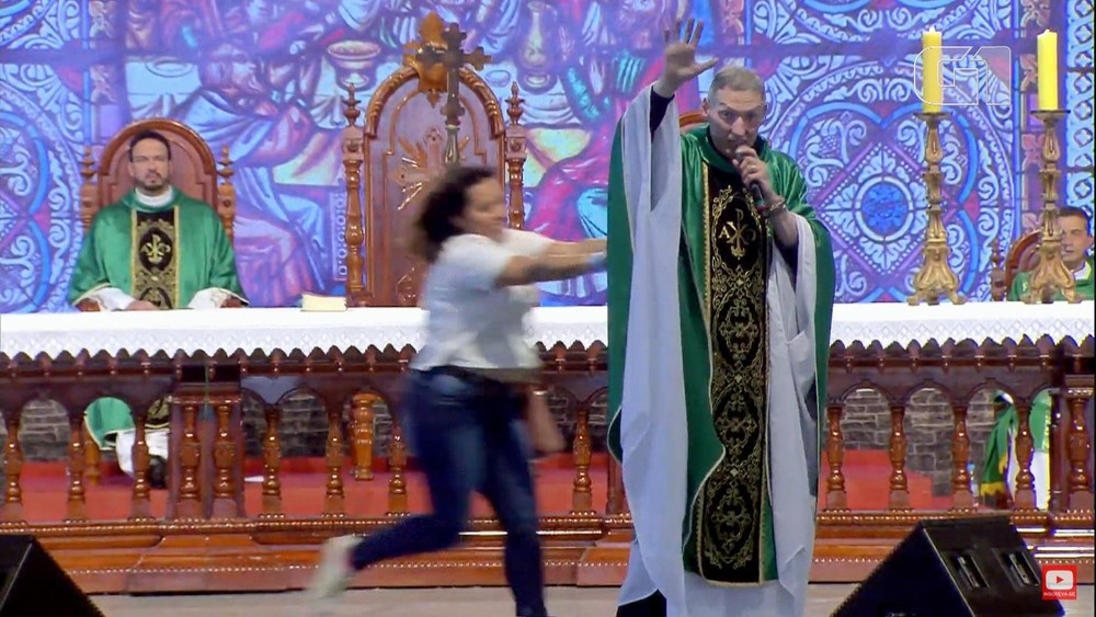 Mulher empurra o Padre Marcelo durante celebração
